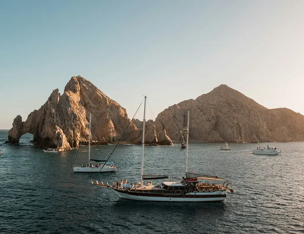 Los Cabos arch with sailing boats at sunset